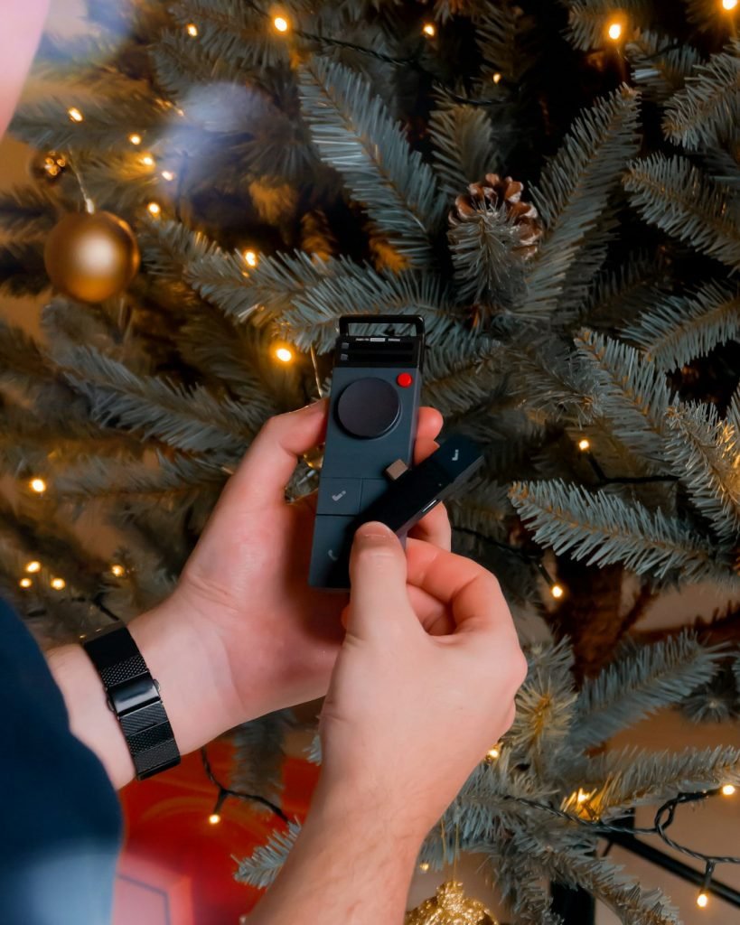 Christmas-themed product and lifestyle photography featuring the HiDock P1 and HiDock P1 Mini. Shot in a cozy home-office desk setup and living/dining room with natural Christmas decor, including a Christmas tree and gift unboxing moments, as well as outdoor winter-inspired shots. The images capture modern work-from-home tools in a warm, seasonal atmosphere blending productivity, technology, and everyday life during the holidays. Photographed by Matúš Gocman in collaboration with HiDock.